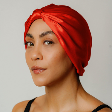 Tomato red organic silk hair bonnet worn on model front view.